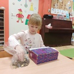 Dziewczynka wrzuca monety do pudełka.jpg